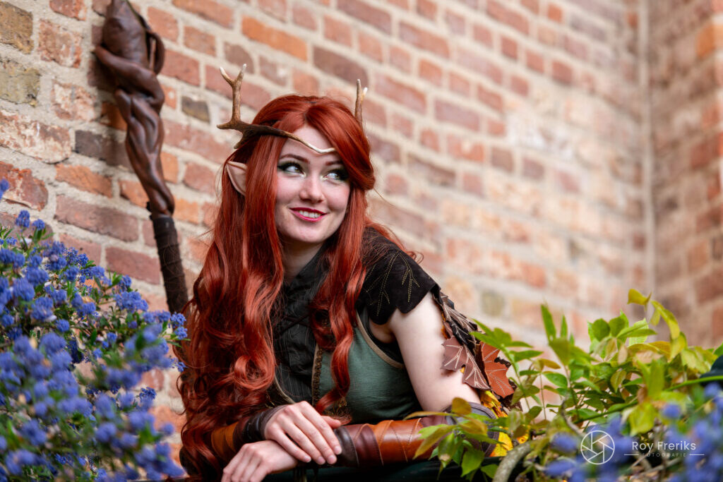 Druïde met rood haar tussen blauwe bloemen bij het kasteel