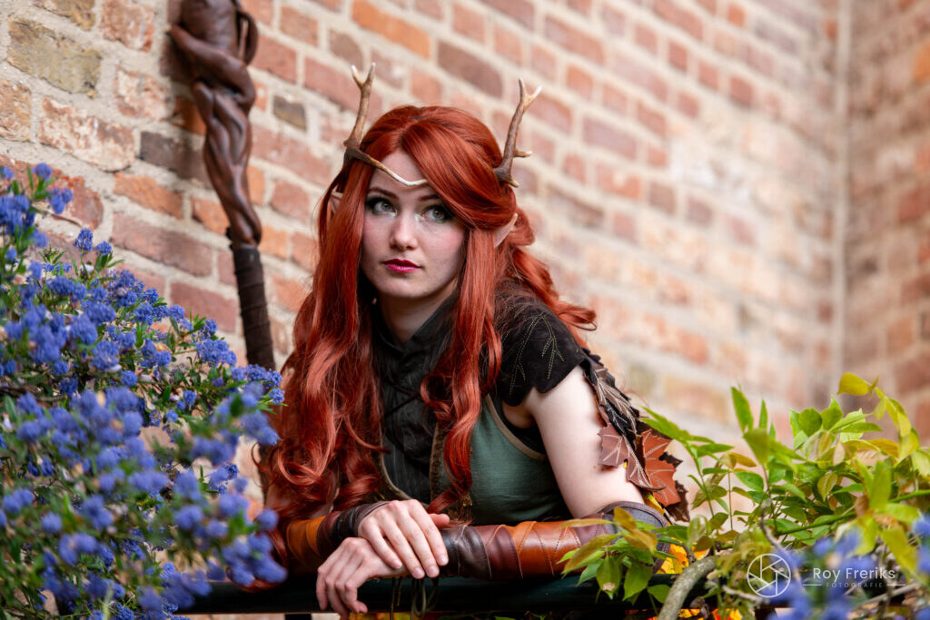 Druïde met rood haar en houten staf bij de kasteelmuur
