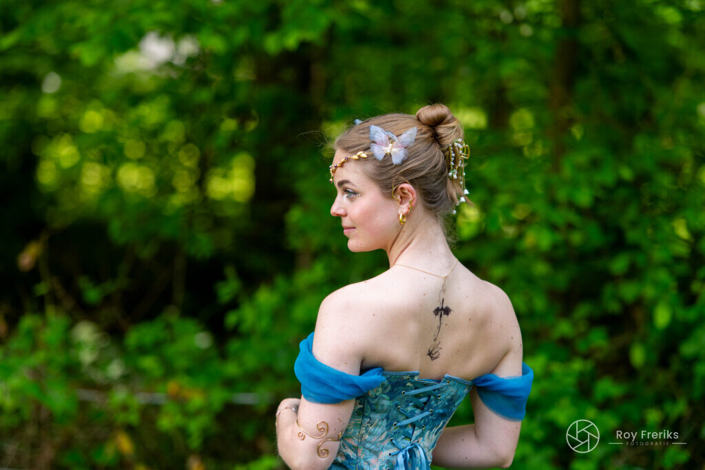 Vrouw in blauwe jurk met vlinderhaarspeld van achteren