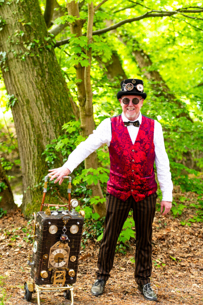 Steampunkheer met rood gilet naast een oude koffer