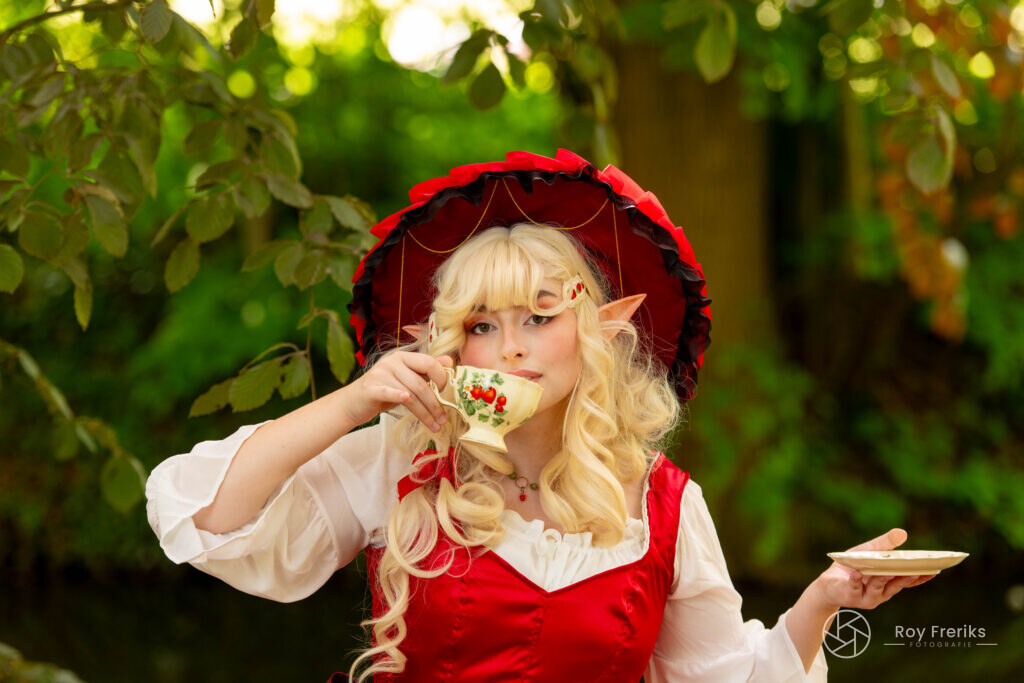 Elf met rode hoed en theekopje tussen het groen