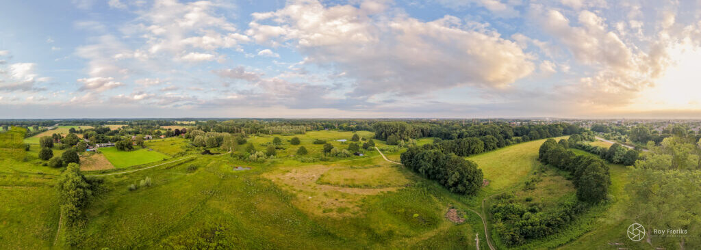 Panorama van glooiend groen landschap onder een wolkenlucht