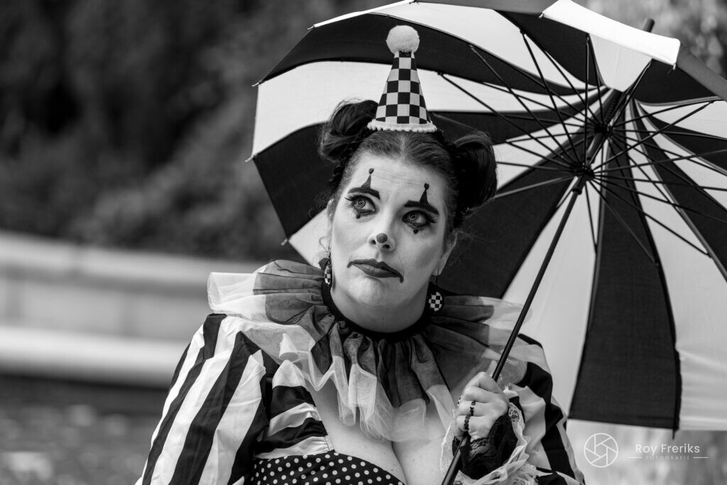 Zwart-witportret van een clown met gestreepte paraplu