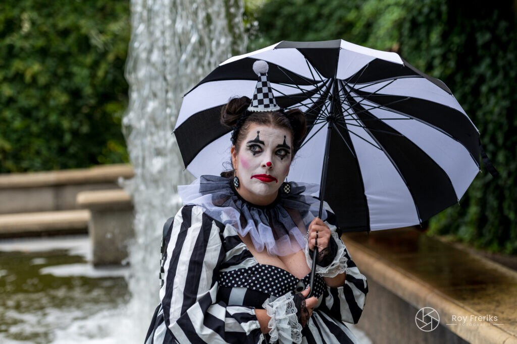 Clown met zwart-witte paraplu voor een waterval