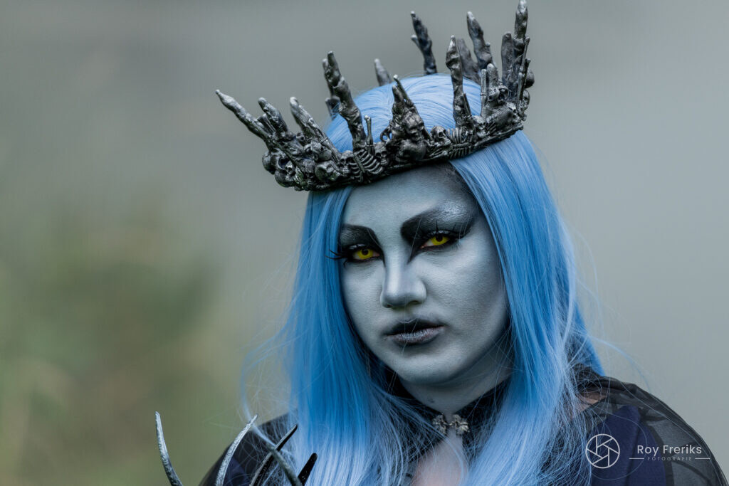 Close-up van een blauw geschminkte vrouw met zwarte kroon