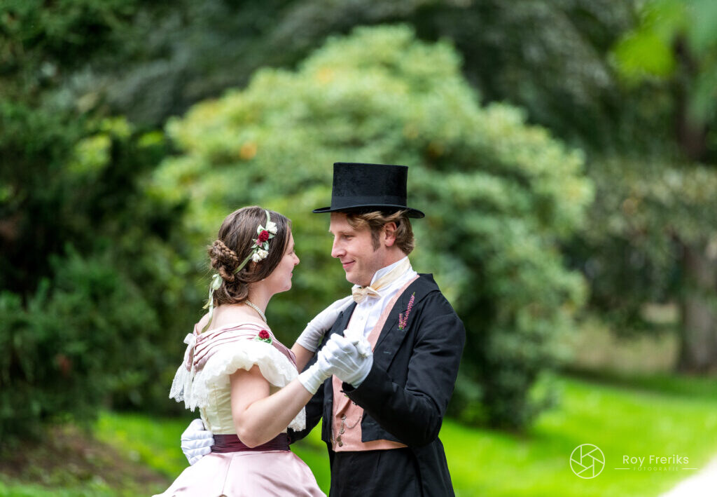 Man en vrouw in victoriaanse kleding dansen in de tuin