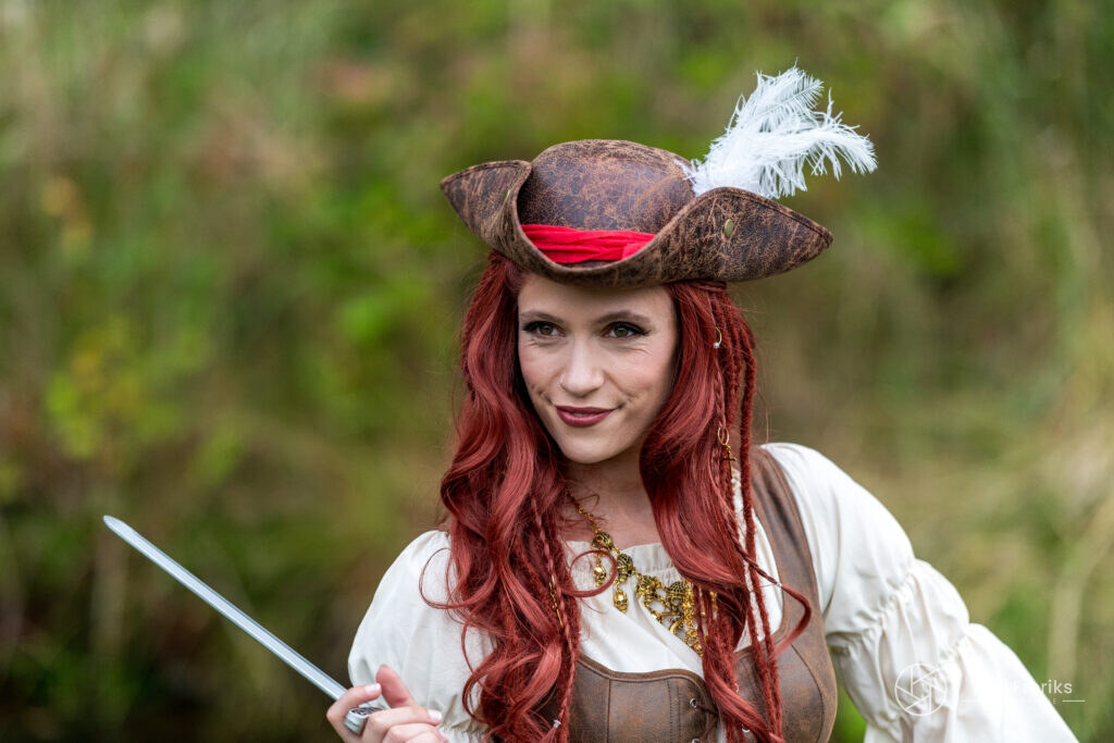 Vrouw met rood haar als piraat met driekante hoed en rapier